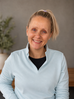 Dr. Laura Sanner, a physical therapist, smiling in a light blue quarter-zip pullover.